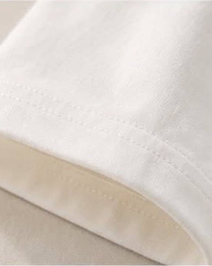 Detail of the shoulder seam and sleeve construction on a white Blanc+ Essential Tee